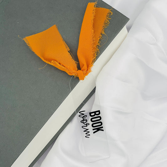 Liebevoll gestaltetes, abgerundetes Lesezeichen aus Acryl mit orangem Chiffonband und beklebt mit schwarzem Folienaufdruck "BOOKWORM"