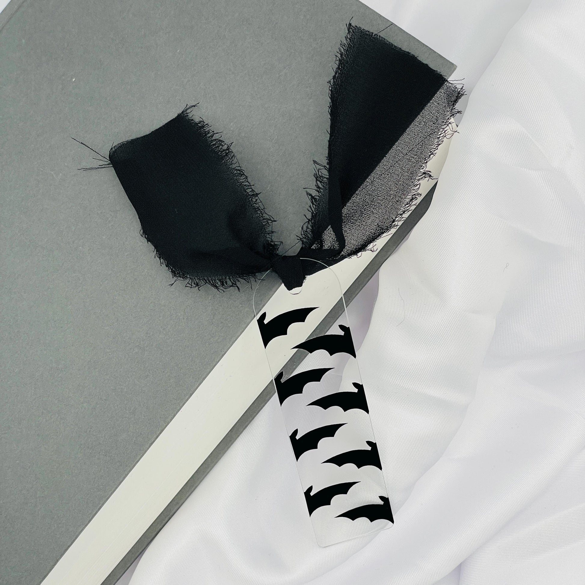 Liebevoll gestaltetes, abgerundetes Lesezeichen aus Acryl mit schwarzem Chiffonband und beklebt mit schwarzer Folie im Muster von Fledermausflügeln