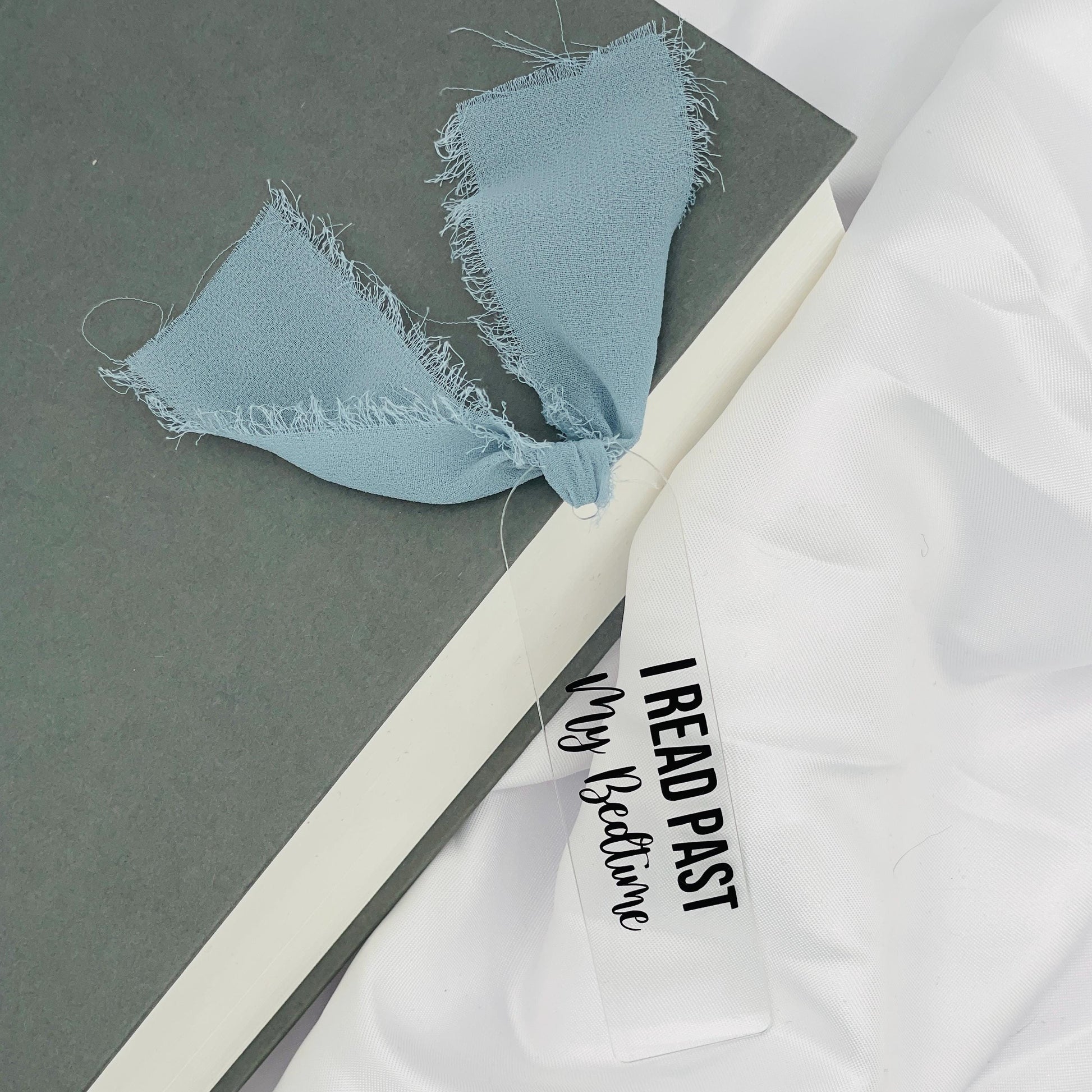 Liebevoll gestaltetes, abgerundetes Lesezeichen aus Acryl mit blau-grauem Chiffonband und beklebt mit schwarzem Folienaufdruck "I read past my Bedtime"
