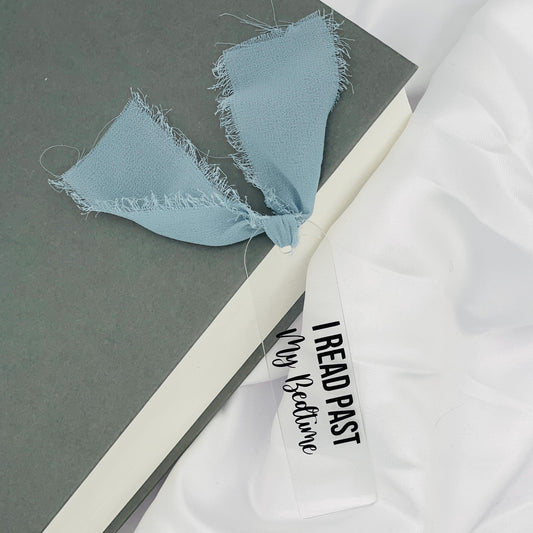 Liebevoll gestaltetes, abgerundetes Lesezeichen aus Acryl mit blau-grauem Chiffonband und beklebt mit schwarzem Folienaufdruck "I read past my Bedtime"