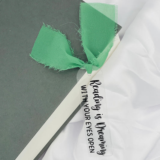 Liebevoll gestaltetes, abgerundetes Lesezeichen aus Acryl mit hellgrünem Chiffonband und beklebt mit schwarzem Folienaufdruck "Reading is Dreaming with your eyes open"