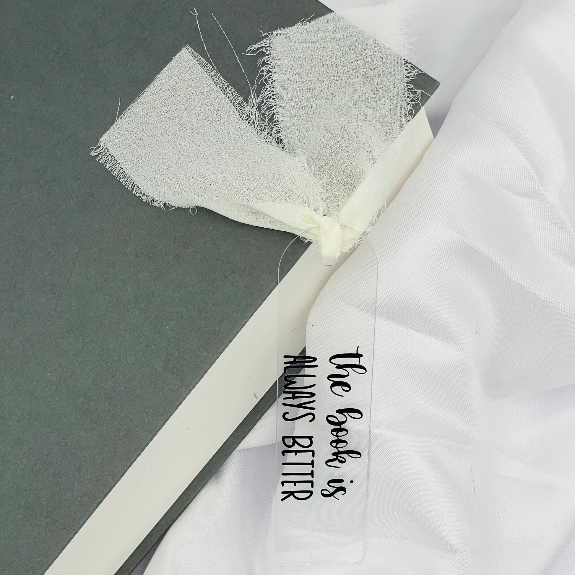 Liebevoll gestaltetes, abgerundetes Lesezeichen aus Acryl mit cremefarbenem Chiffonband und beklebt mit schwarzem Folienaufdruck "the book is always better"