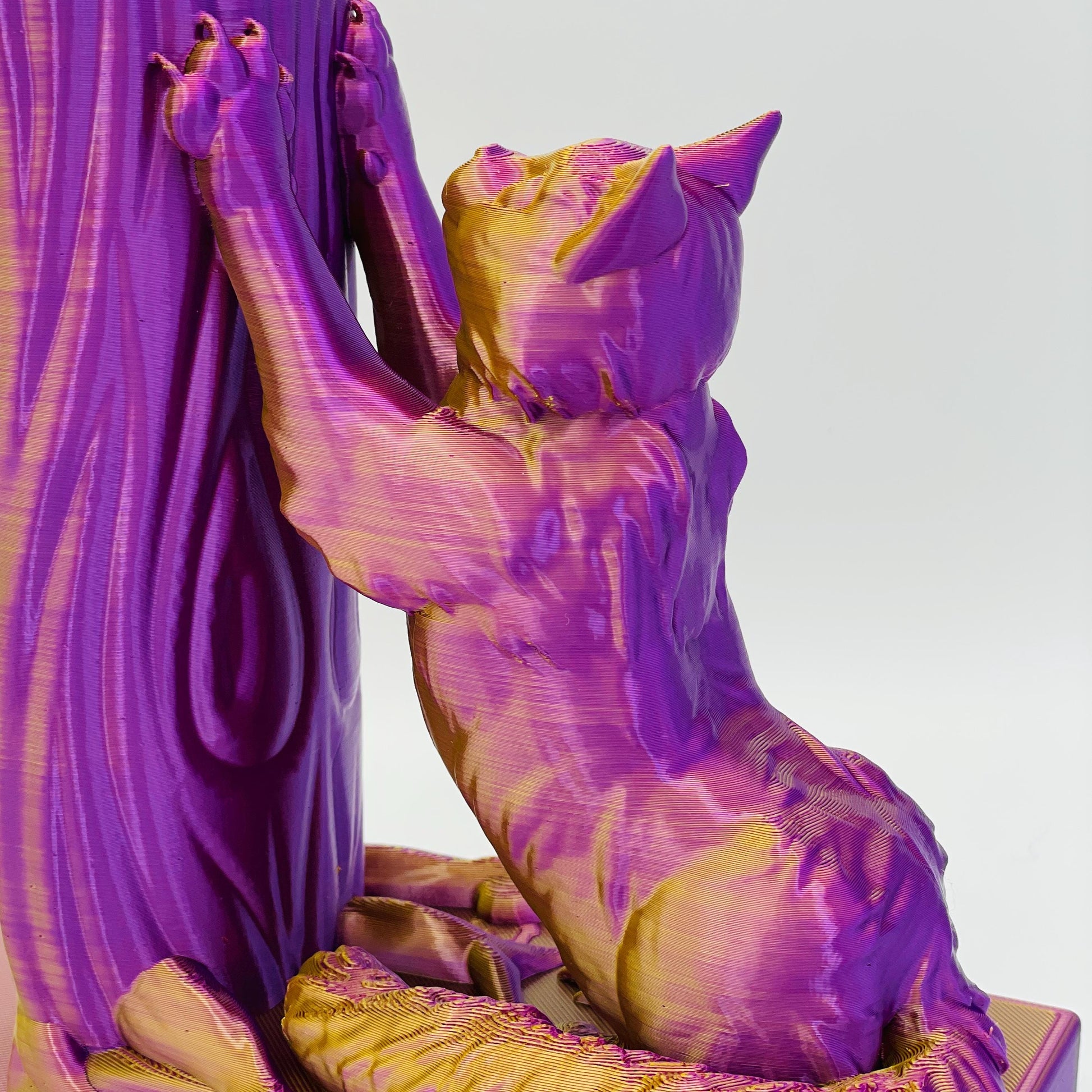 Diagonale, detaillierte Ansicht einer 3D-gedruckten Buchstütze einer süßen, sitzenden Katze in Seitenansicht, die sich mit ihren Vorderpfoten an einen Baum streckt im Farbton Lila-Gold
