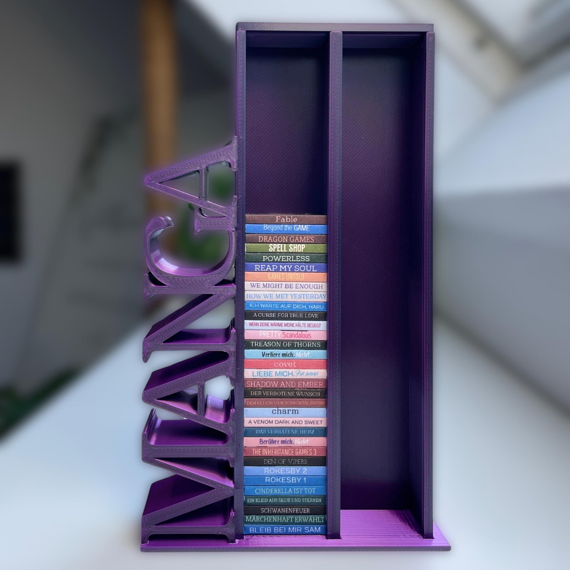 Milieuansicht 3D-gedruckter Lesezielturm im Farbton Blau-Lila-Pink bietet Platz für 100 Mini-Bücher mit vertikalem "MANGA" Schriftzug befüllt mit über 30 beklebten Mini-Büchern