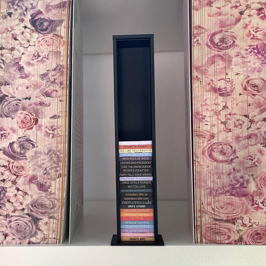 Milieuansicht 3D-gedruckter Lesezielturm im Farbton Matt Schwarz bietet Platz für 50 Mini-Bücher, zwischen zwei Büchern mit Blumenfarbschnitt
