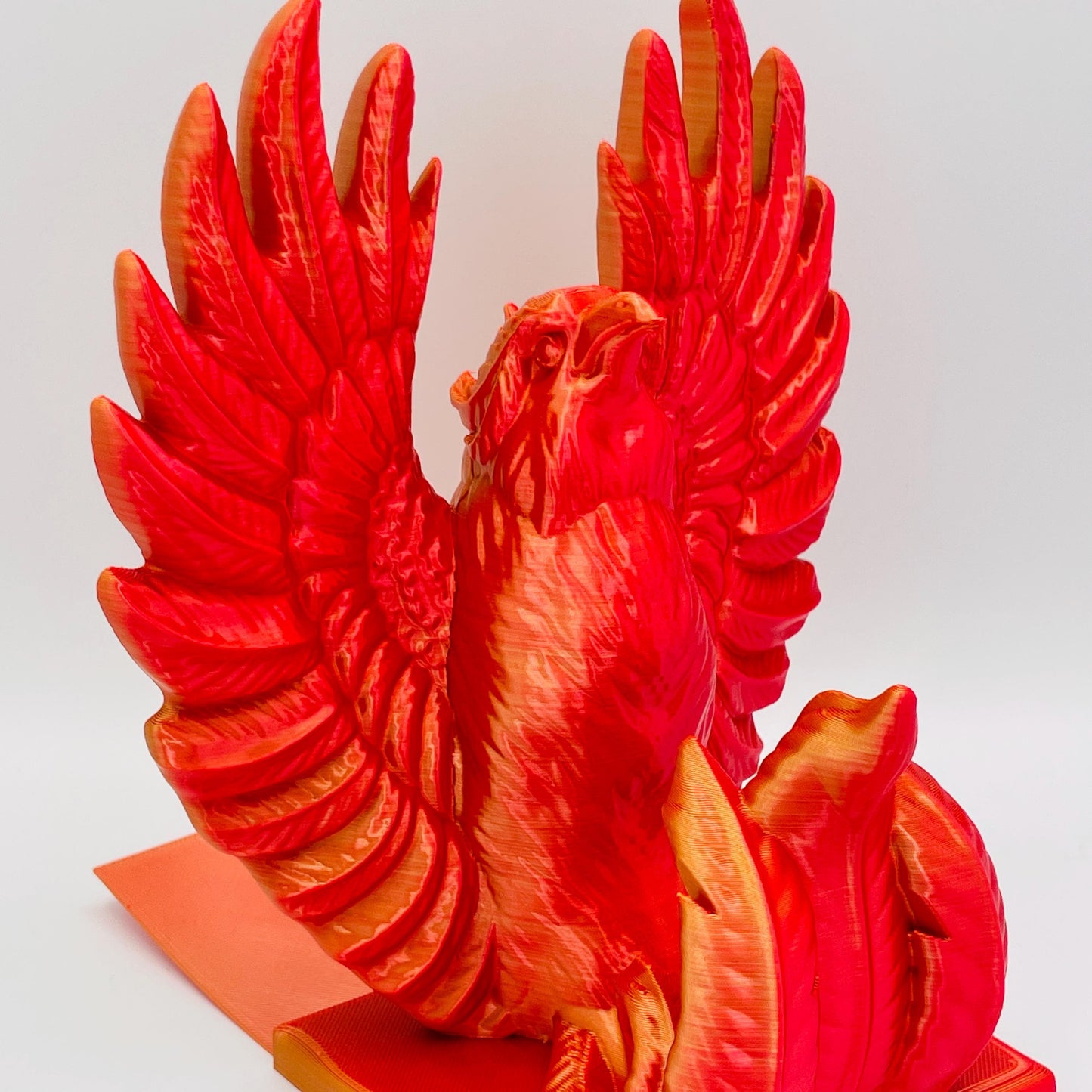 Detaillierte Ansicht einer 3D-gedruckten Buchstütze eines stolzen Phönix mit gestreckten Flügeln im Farbton Rot-Gold