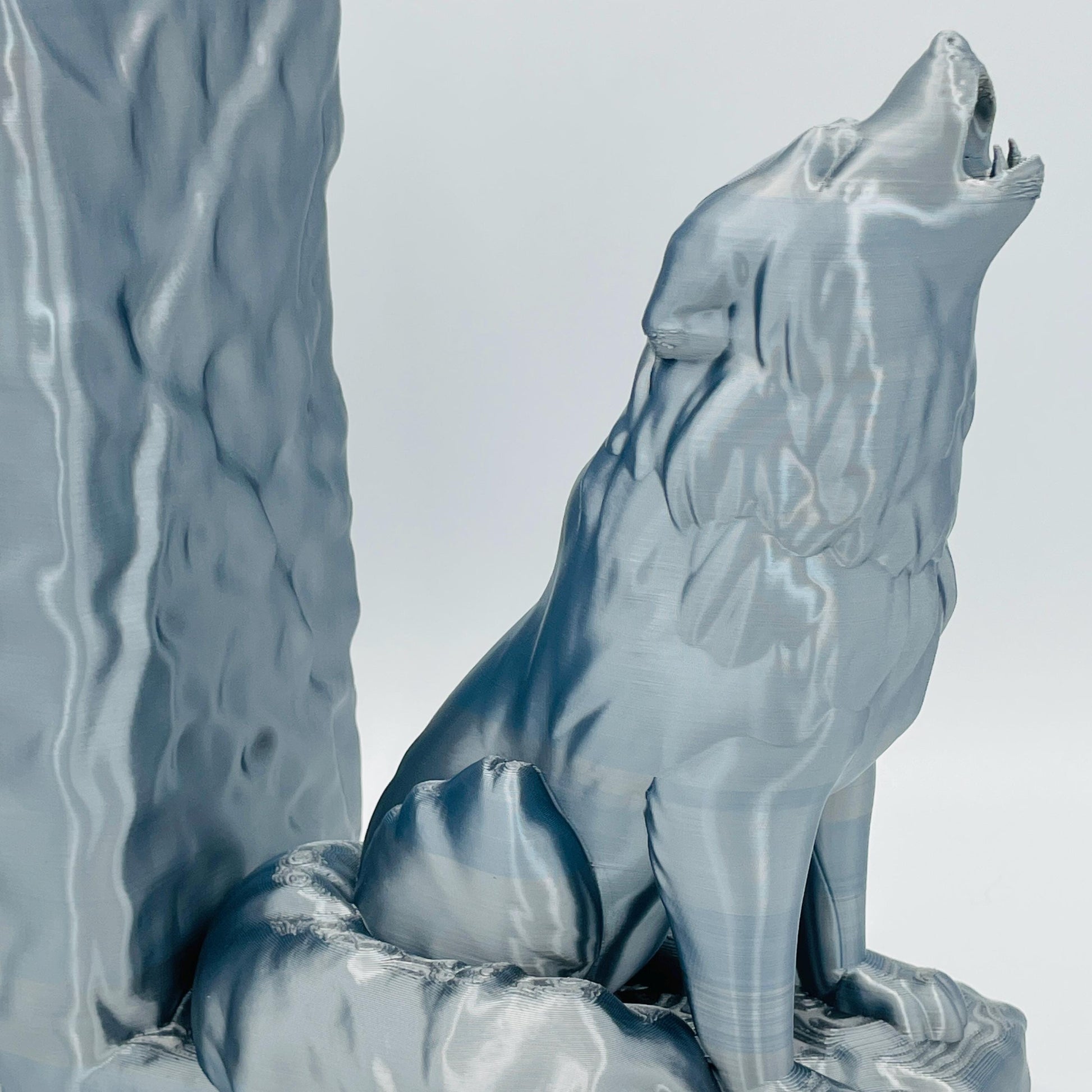 Detaillierte Nahaufnahme einer 3D-gedruckten Buchstütze eines starken, sitzenden Wolfes, der zum Himmel heult/jault, im Farbton Silber
