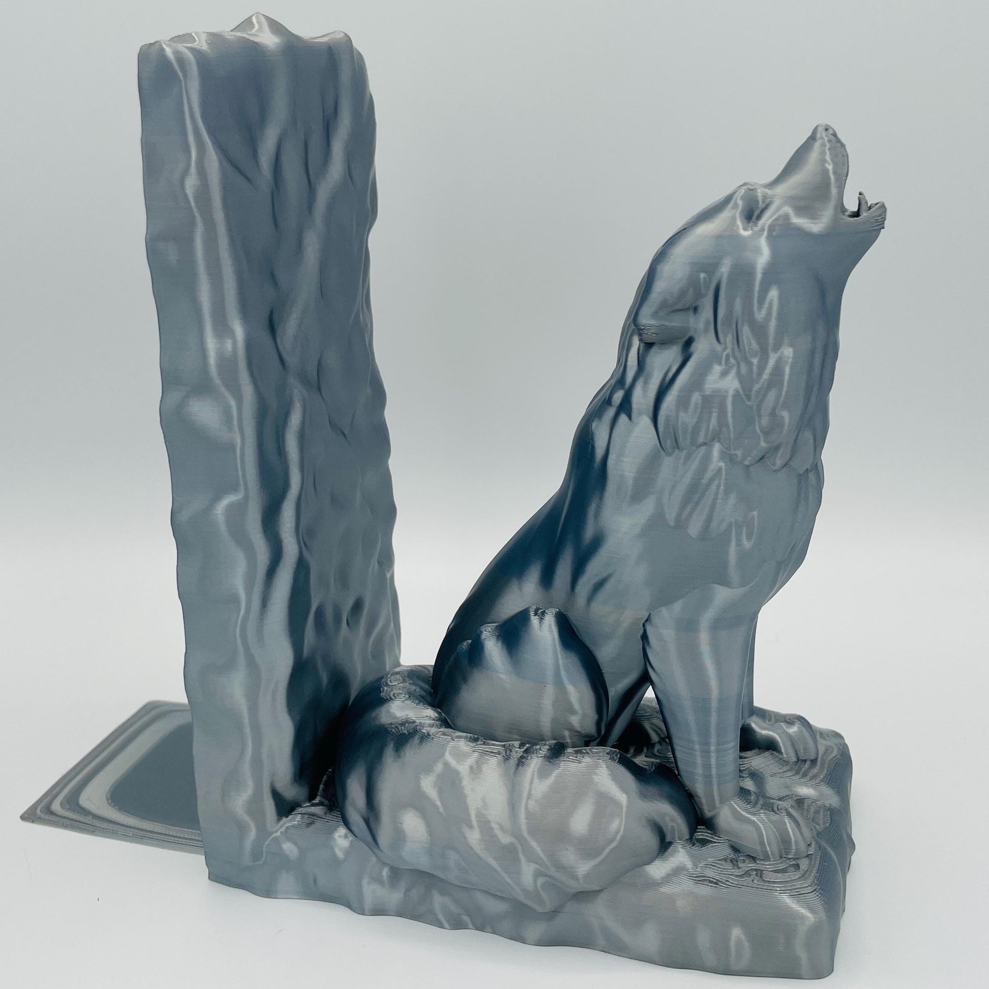 Detaillierte Seitenansicht einer 3D-gedruckten Buchstütze eines starken, sitzenden Wolfes, der zum Himmel heult/jault, im Farbton Silber